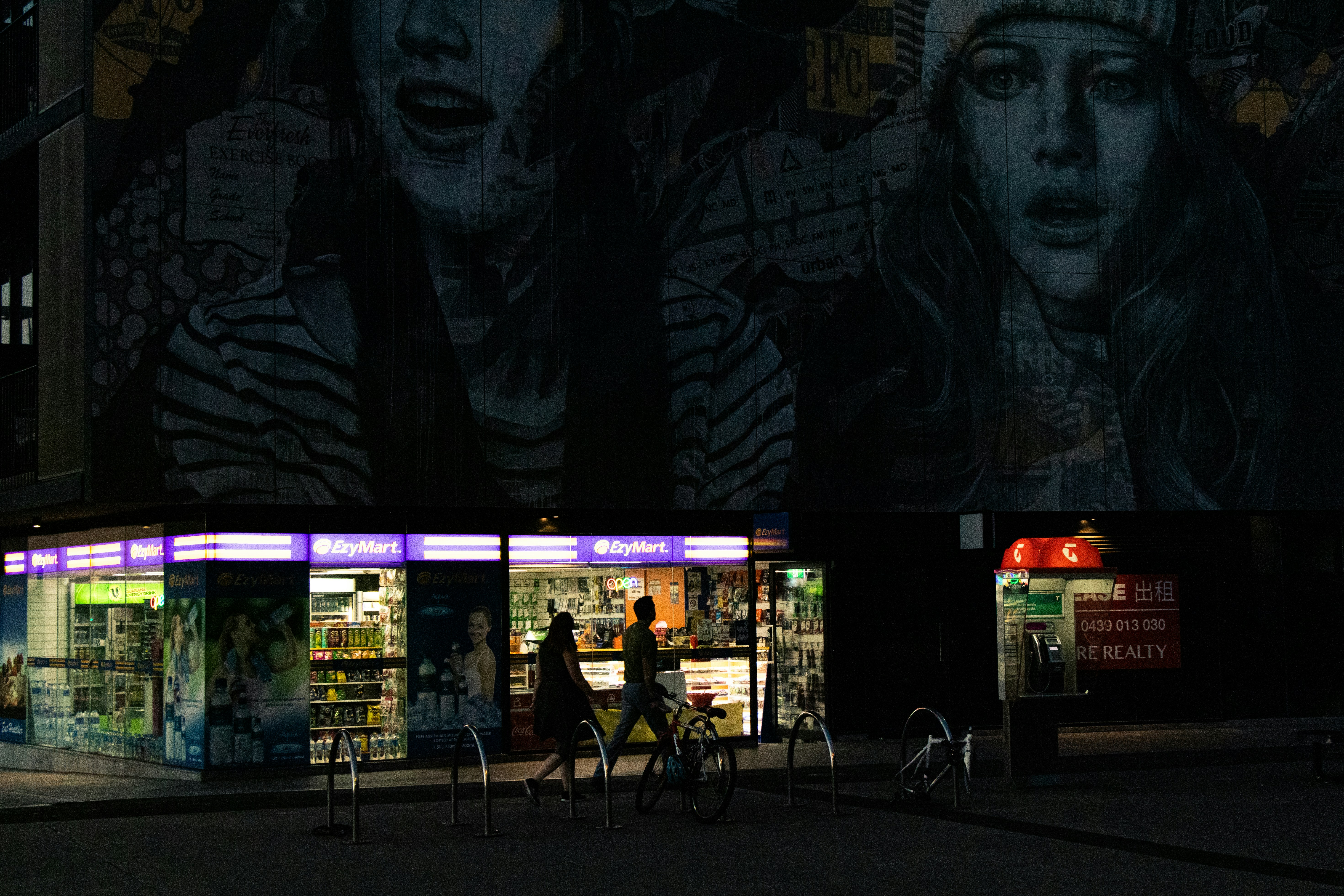 Cyclist passing a lit shopfront at night