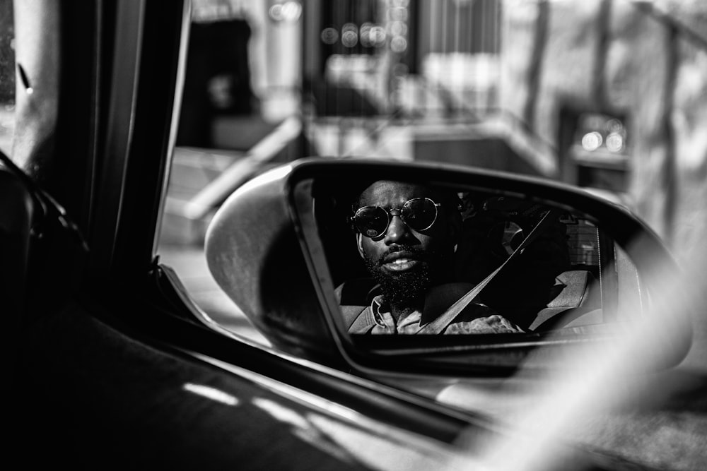 grayscale photography of man sitting on vehicle seat