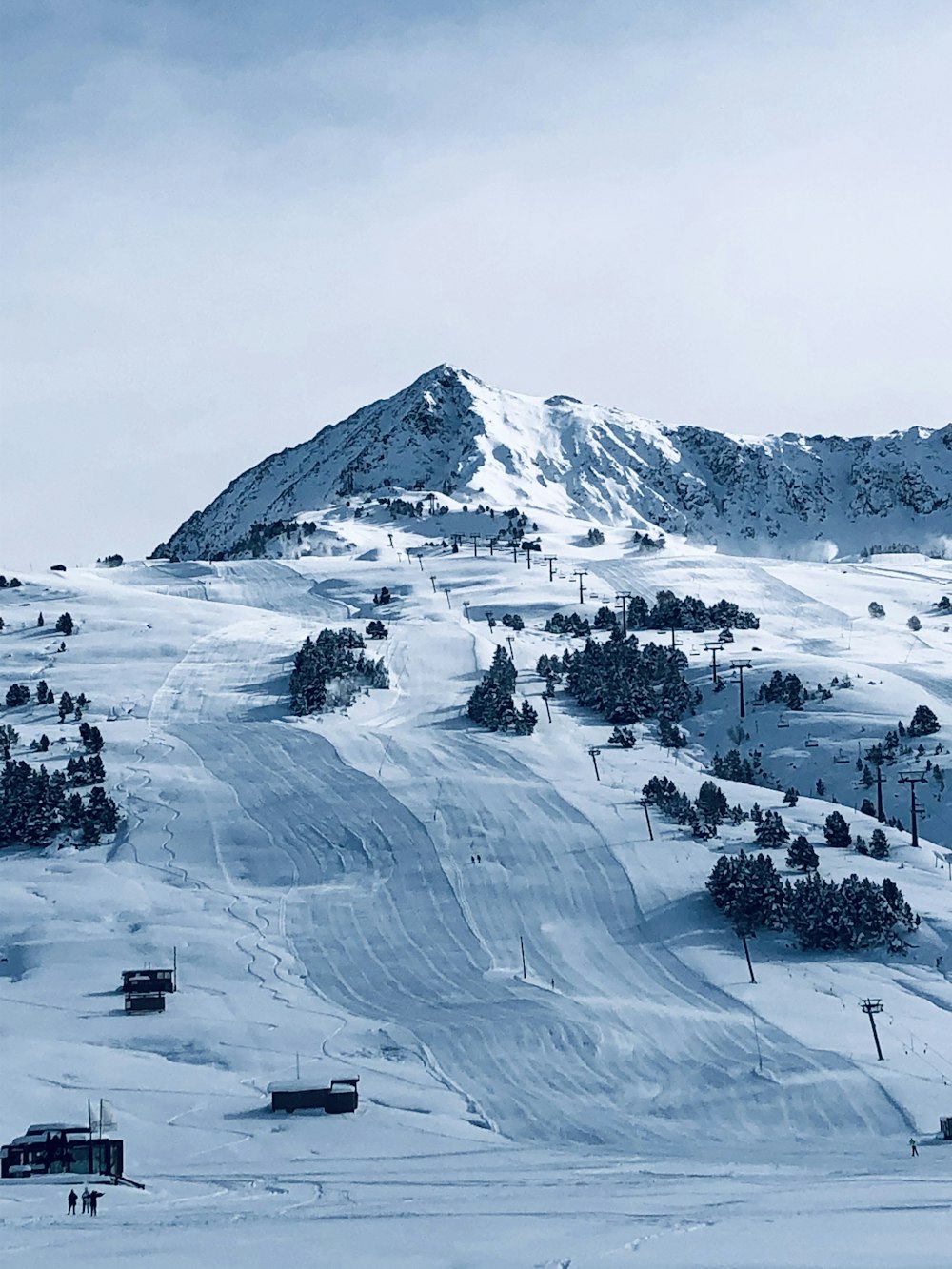 Photographie aérienne de personnes près des maisons et des champs couverts de neige sous un ciel blanc et bleu pendant la journée