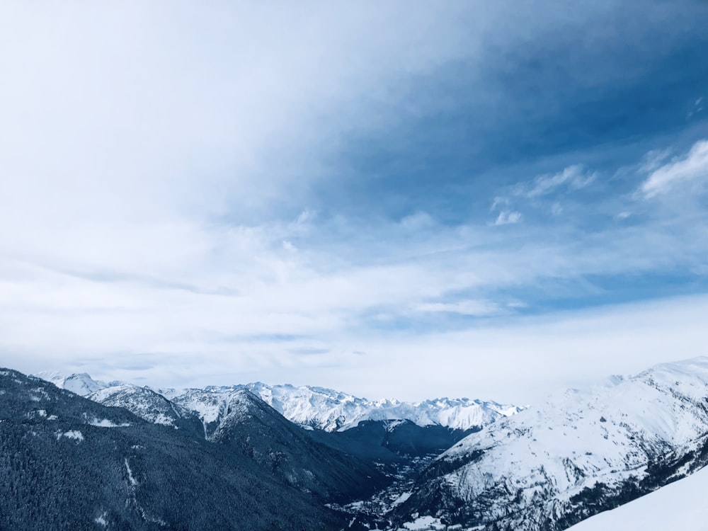 Luftaufnahme von schneebedeckten Bergen unter weißem und blauem Himmel während des Tages
