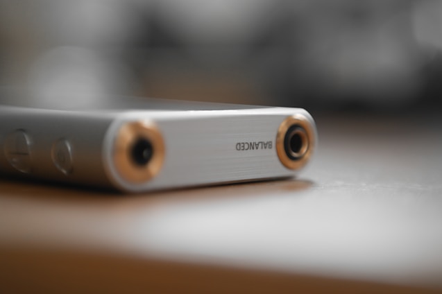 Close-up of a sleek bronurd wireless audio device resting on a wooden table, highlighting its aluminum and glass finish.