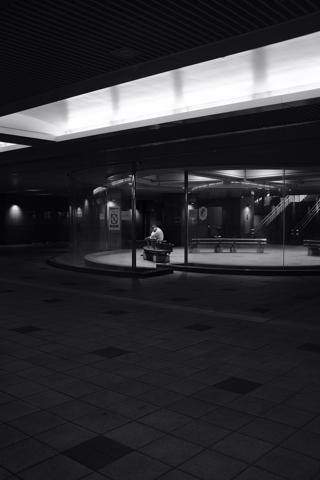 grayscale photography of person sitting near road