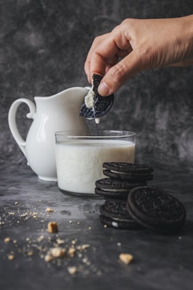 person holding biscuit dripping it in milk