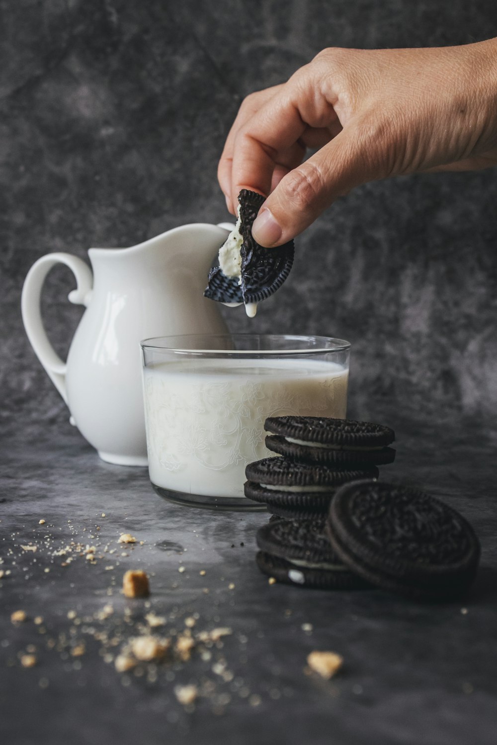 persona sosteniendo una galleta goteándola en leche