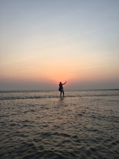 silhouette photo of man standing at middle of sea