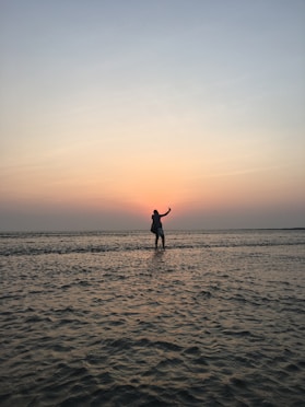 silhouette photo of man standing at middle of sea