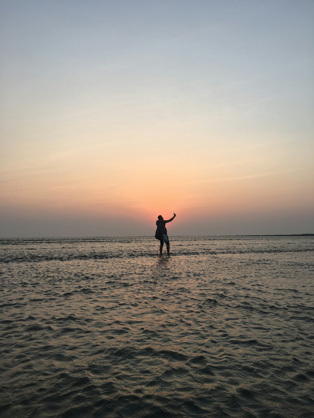 silhouette photo of man standing at middle of sea