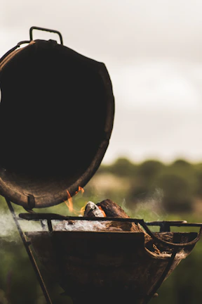 Smoke gently rising from a BBQ grill, with glowing embers and wood chips visible.