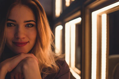 A warm, elegant photo of a smiling woman enjoying a moment of self-care surrounded by natural light and soft beige tones.