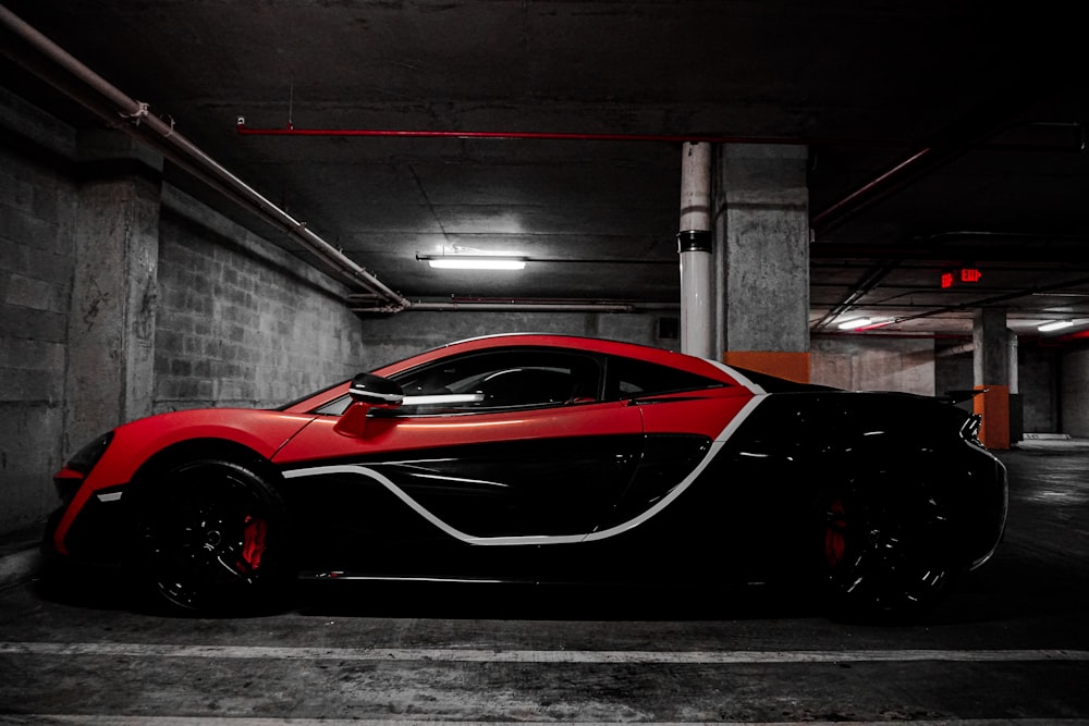 red and black sports coupe parked front of wall