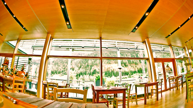 Softly lit corner of the restaurant with minimalist furniture and a view of the misty Furnas landscape through large windows.
