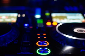 Close-up of a mixer deck glowing with vivid LEDs during a peak moment in the set.