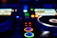 Close-up of a DJ mixing tracks with vibrant neon lights reflecting off sleek equipment.