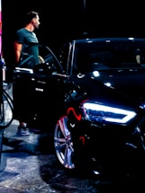 A professional chauffeur opening the car door for a passenger in a sleek black vehicle.