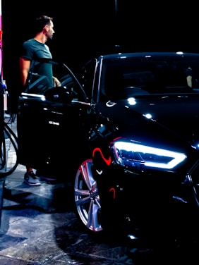 A professional driver opening the car door for a passenger in a sleek black vehicle.