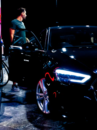 A friendly valet helping a happy customer into their car at night.