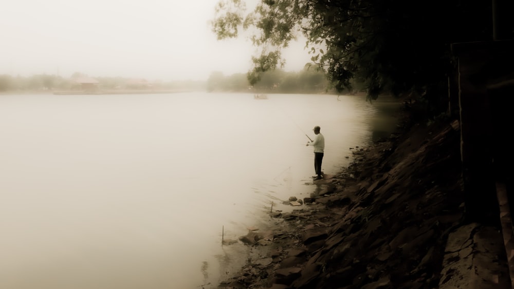 low-light photography of man fishing on river