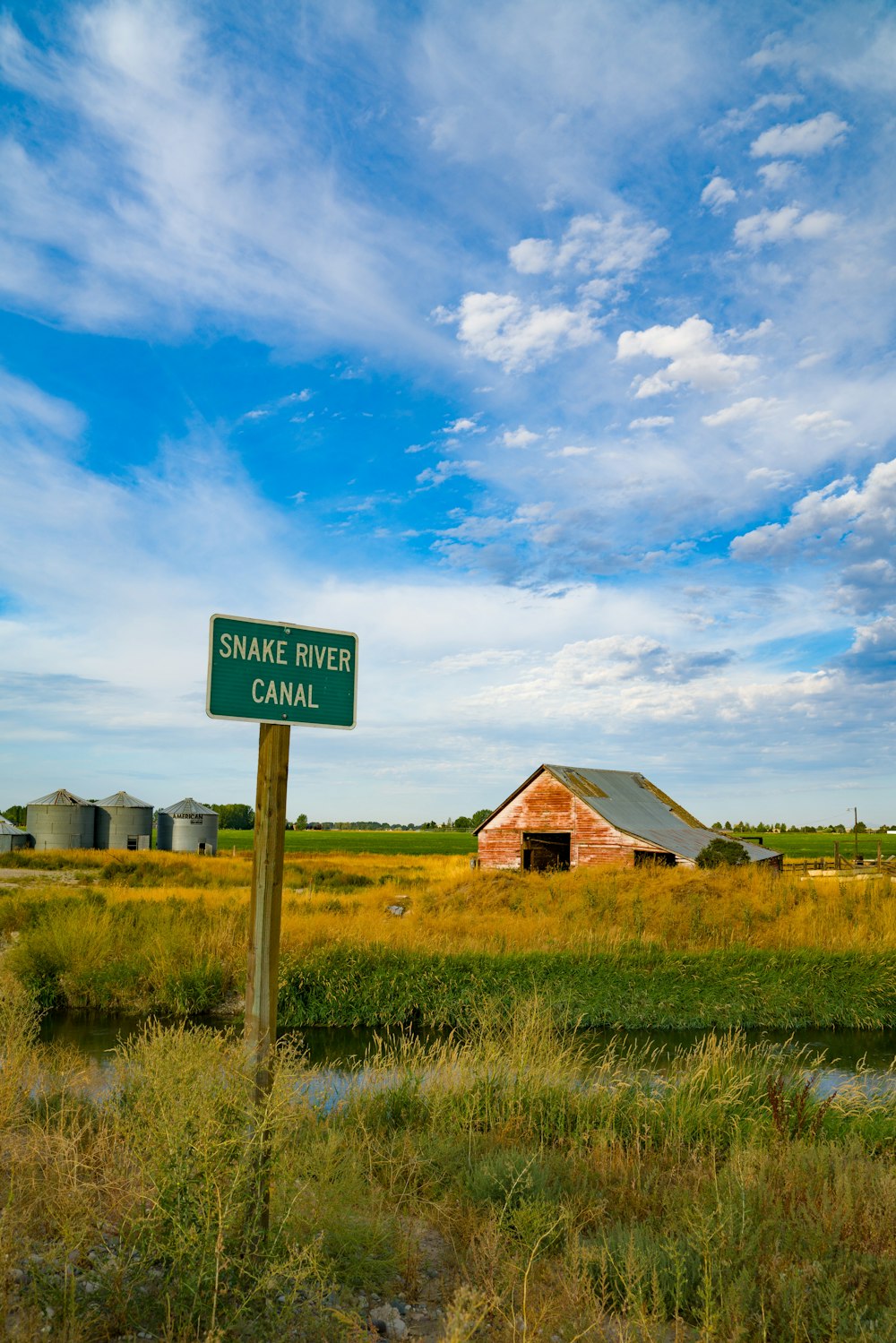 brown barn on field under blue sky and white clouds