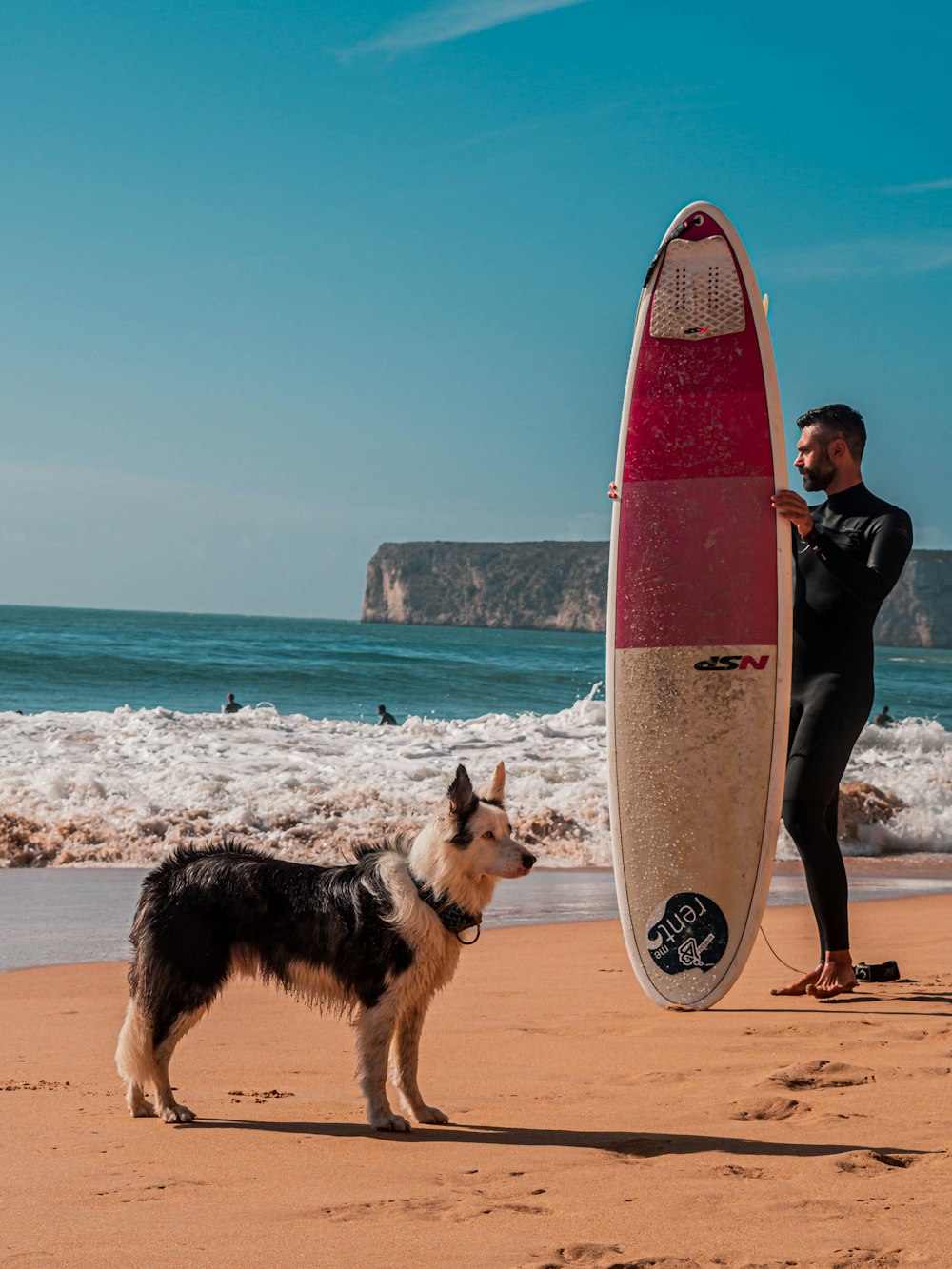 man standing beside surfboard on seashore
