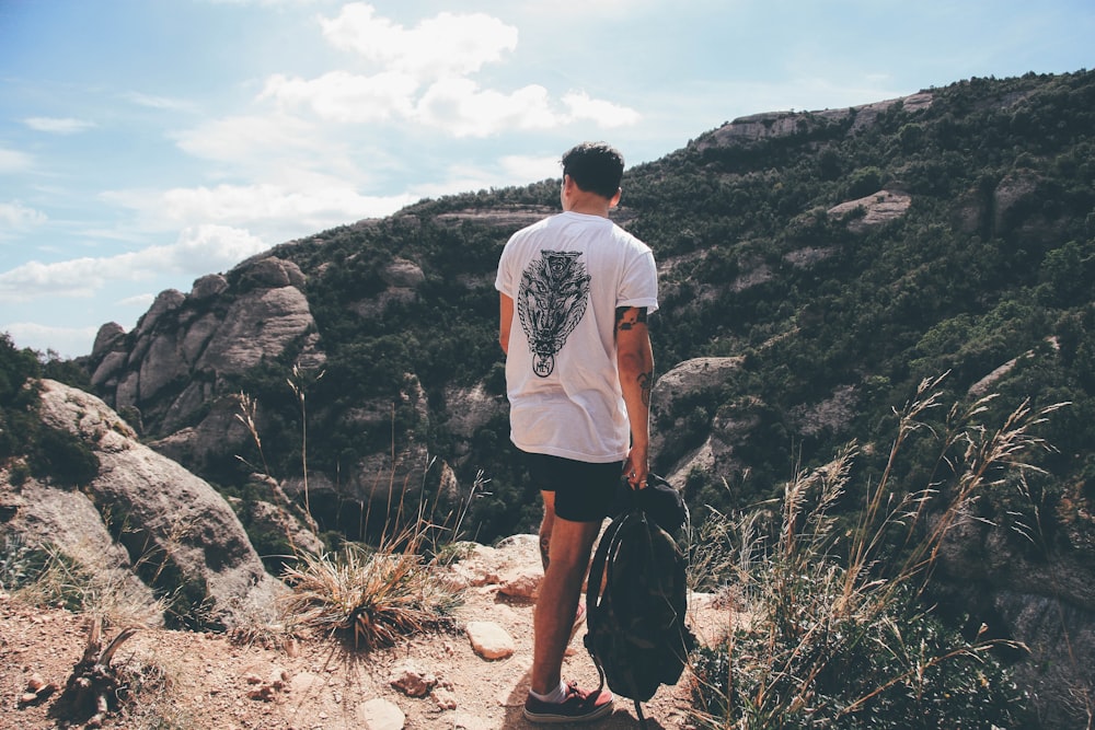 hombre sosteniendo una mochila de pie cerca del camino