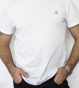 man wearing white crew-neck shirt and black denim jeans with hands in pocket