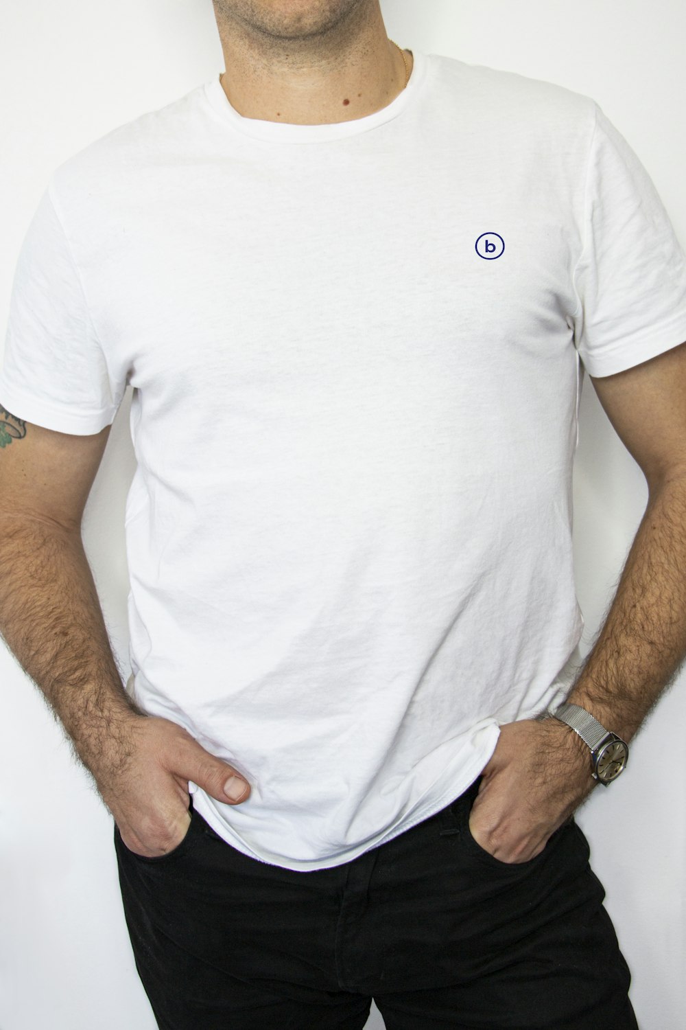 Hombre con camisa blanca de cuello redondo y jeans de mezclilla negros con las manos en el bolsillo