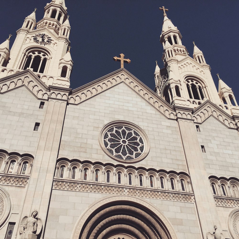 low-angle photography of white cathedral under a calm blue sky