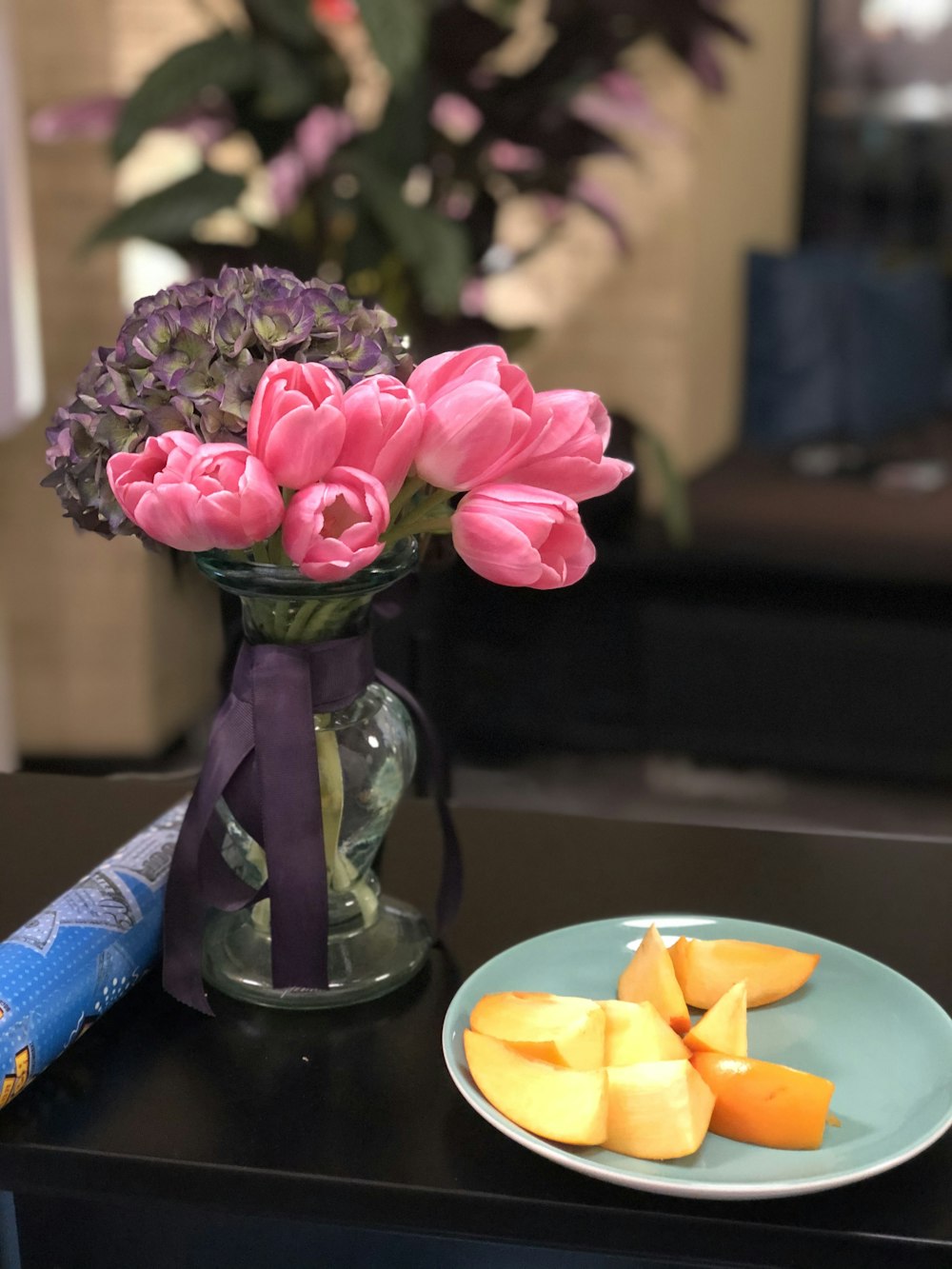 pink tulip flowers in vase near sliced fruits