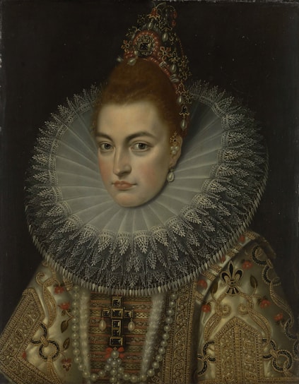 A woman is depicted in a formal portrait wearing an elaborate dress adorned with intricate embroidery and pearls. Her hair is styled in an updo decorated with ornaments, and she wears a large lace ruff collar. Her expression is composed and dignified against a dark background.