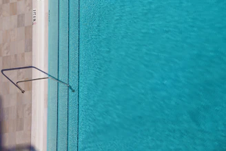 A clean, turquoise pool sparkling under the bright Arizona sun with a maintenance technician checking chemical levels.