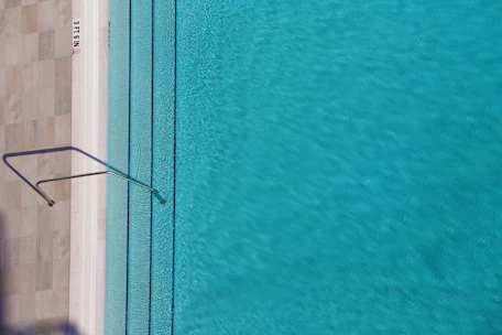 A clean, turquoise pool sparkling under the bright Arizona sun with a maintenance technician checking chemical levels.
