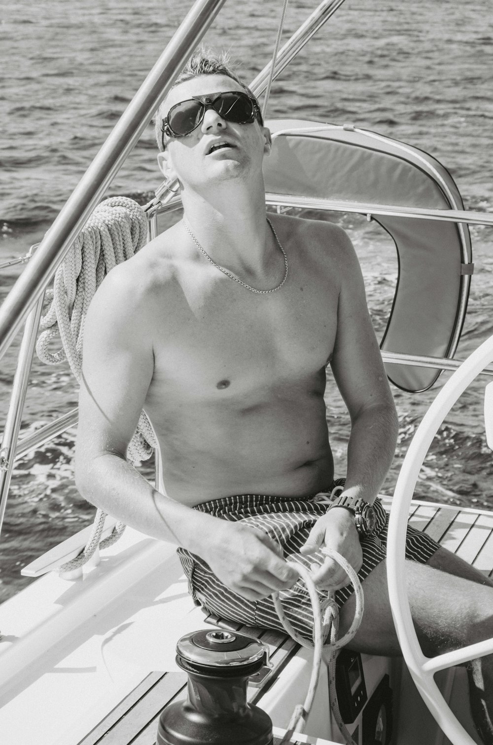 Graustufenfotografie eines Mannes, der auf einem Boot sitzt