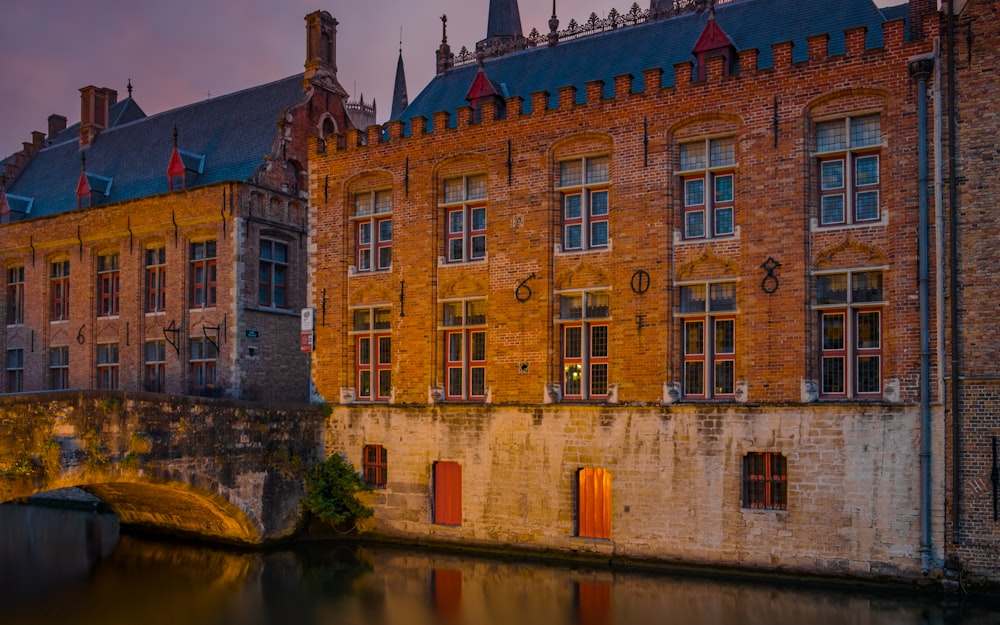 brown concrete house beside canal with arch bridge