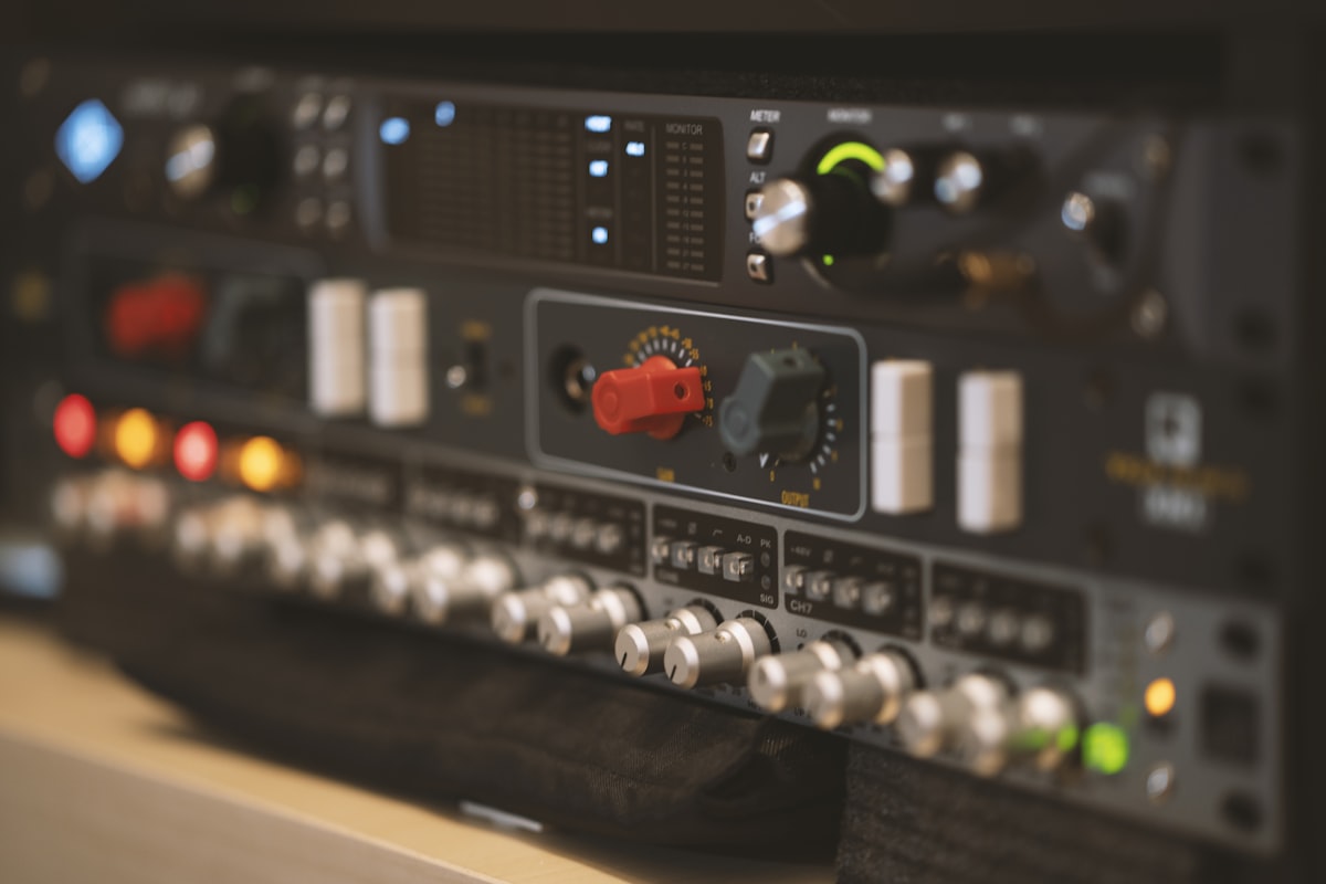 Black and gray electronic audio processor unit with control knobs and input buttons on a dark surface