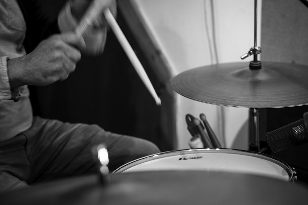 greyscale photo of person playing drums