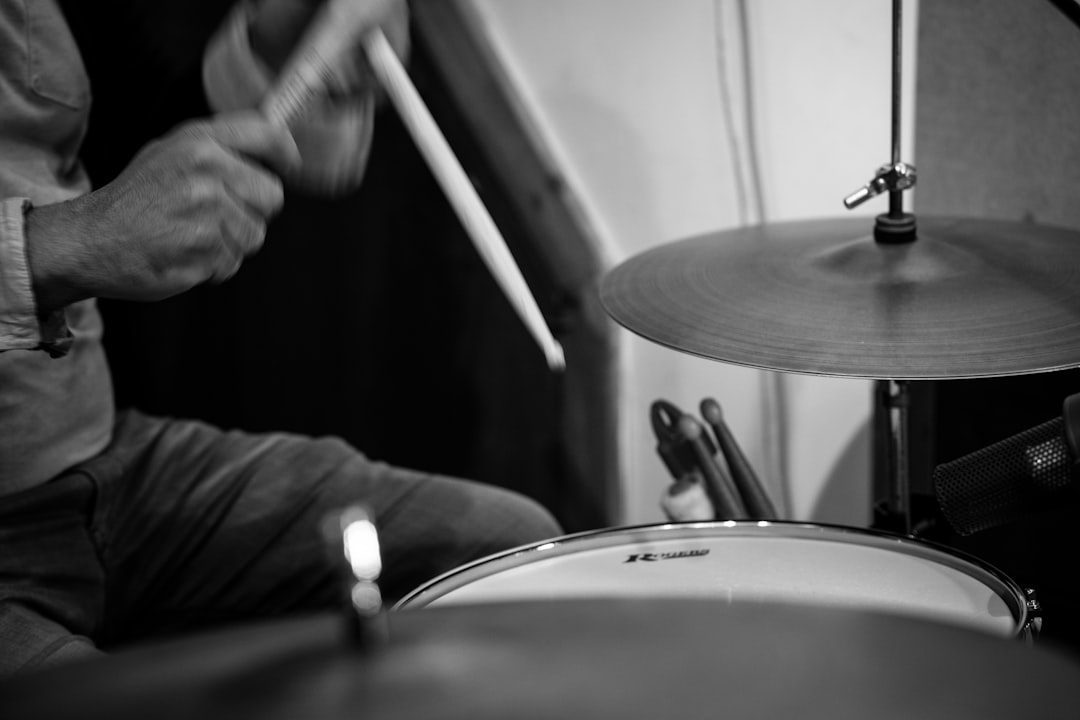 greyscale photo of person playing drums