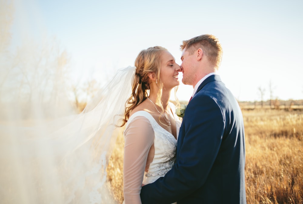 man wearing blue suit trying to kiss woman wearing white wedding gown