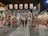 A vibrant festival setting with numerous paper lanterns overhead, stalls filled with colorful decorations, and people walking and browsing. The atmosphere is lively with a variety of items on display, creating a bustling and cultural ambiance.