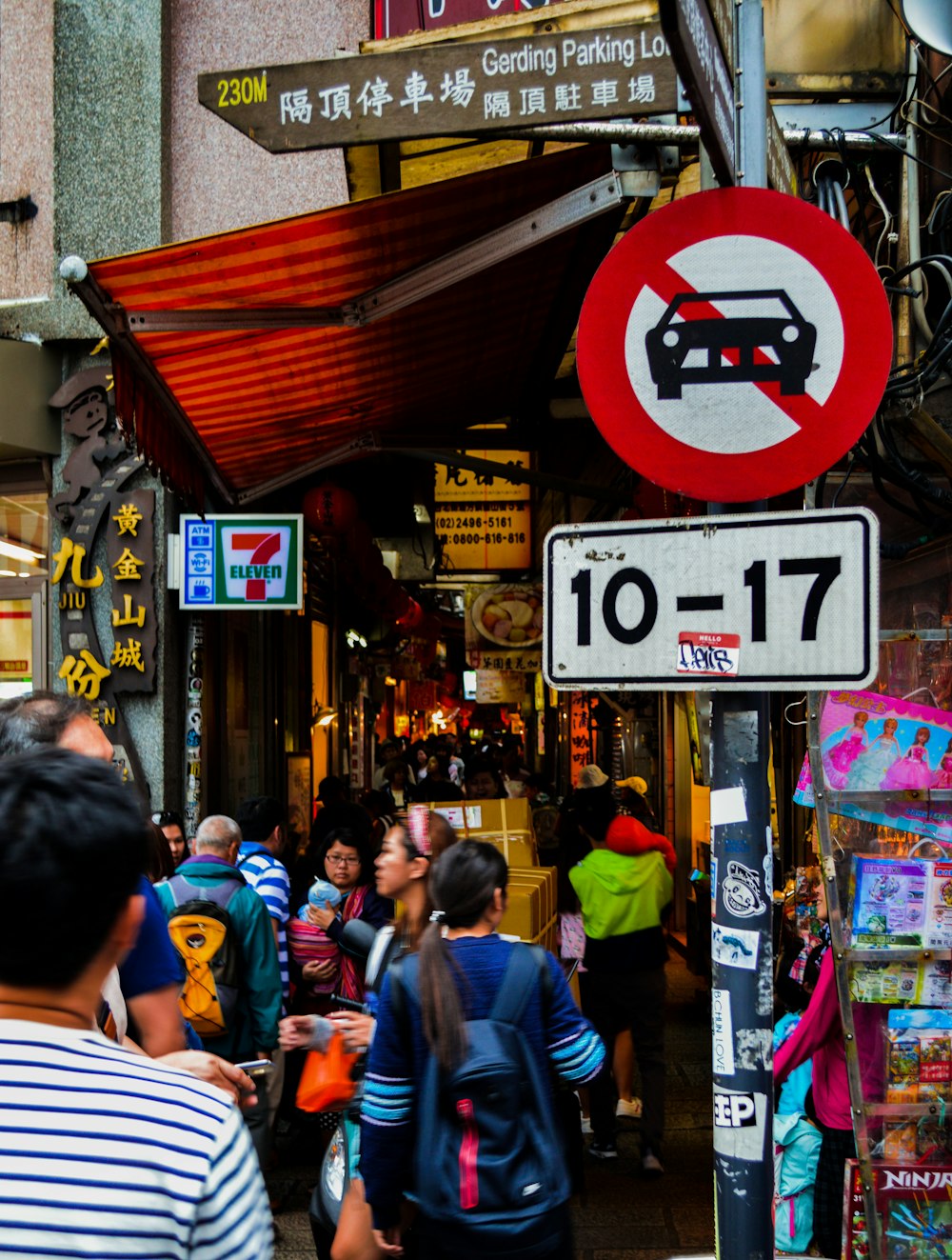 people walking beside vehicle no entry sign