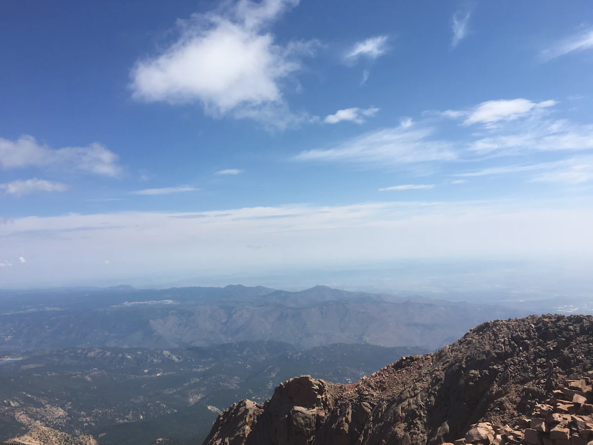 Looking out from a rocky high point in Colorado over hazy ridges toward the plains