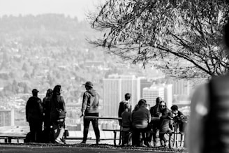 A diverse group of community members gathered outdoors, engaging in a lively discussion around a picnic table.