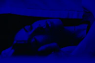 A nighttime scene with soft glowing lights and a person winding down with brainwave music.