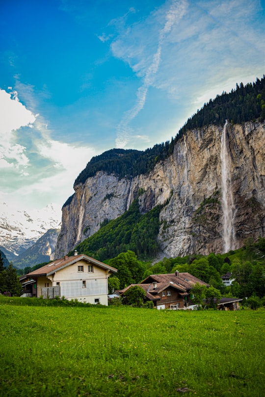 white painted house on grass field beside of mountain scenery in Staubbach Falls Switzerland