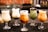 Five glasses of varying iced drinks are arranged in a row on a dark surface. Each glass contains a different type of creamy, colorful beverage, some with toppings like berries and boba pearls. The drinks are set against a blurred background, possibly a café setting.