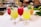 A selection of vibrantly colored tropical cocktails served in elegant glassware, each garnished with fresh mint leaves and decorative skewers. The drinks range in color from yellow to red, showcasing a refreshing appearance. They are placed on a white surface with a blurred background suggesting a bar setting.