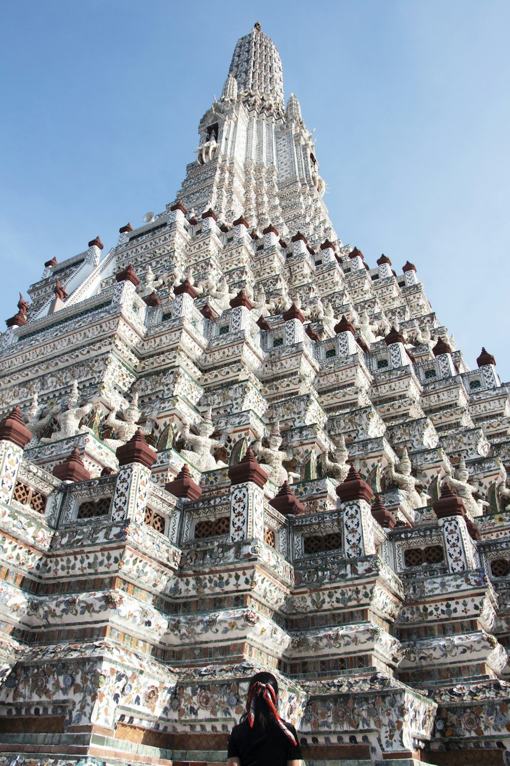 person standing near Hindu temple under blue and white sky