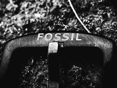 Close-up of a metal belt buckle engraved with Persian calligraphy symbolizing strength.