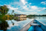 house near blue body of water surrounded with green trees under white and blue sky