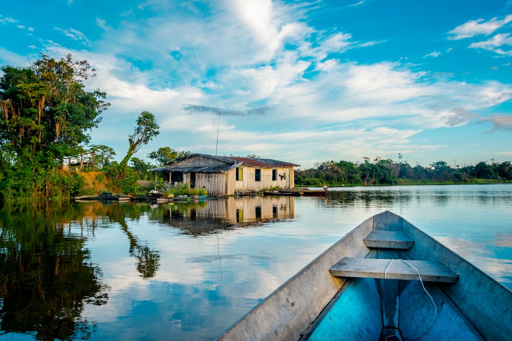 casa perto do corpo azul de água cercado com árvores verdes sob o céu branco e azul