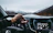 Driver smiling while using a šarvys head unit on a scenic mountain highway.